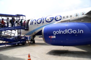 Passengers boarding a blue and white airplane, with "IndiGo" written in blue letter across the side