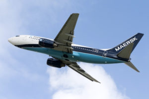 A WHITE, DARK BLUE AND LIGHT BLUE MAERSK LABELLED AIRPLANE IS FLYING THROUGH THE SKY.