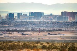 PLANES SIT ON THE TARMAC IN A DESERT AIRPORT, FRAMED BY A CLUSTER OF MODERN TOWERS BEHIND