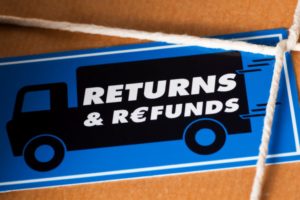 A BLUE SHIPPING LABEL ON A BROWN-PAPER-WRAPPED BOX READS RETURNS AND REFUNDS