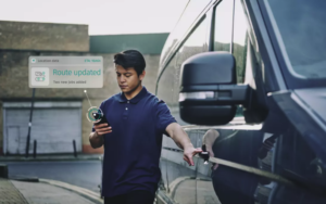 A man holding a phone next to a blue delivery van